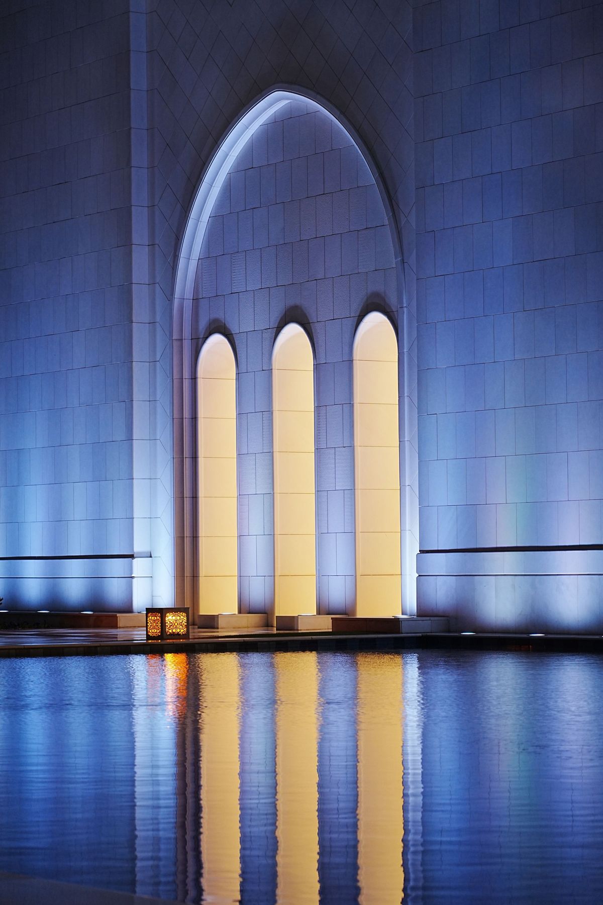 Arcos iluminados junto a un espejo de agua al anochecer